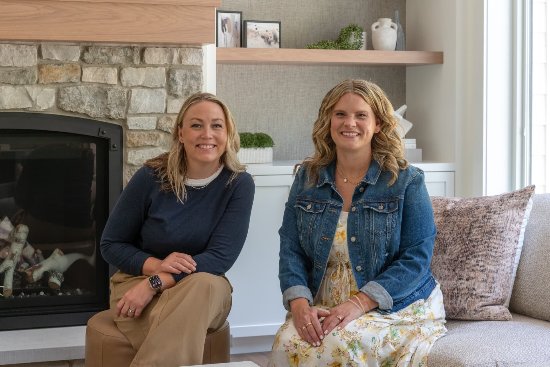 Amy Pottenger and her Refresh Design partner seated by a stone fireplace